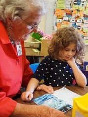 Foster Grandparent volunteer reading with student