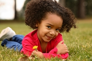 Child on lawn with flower
